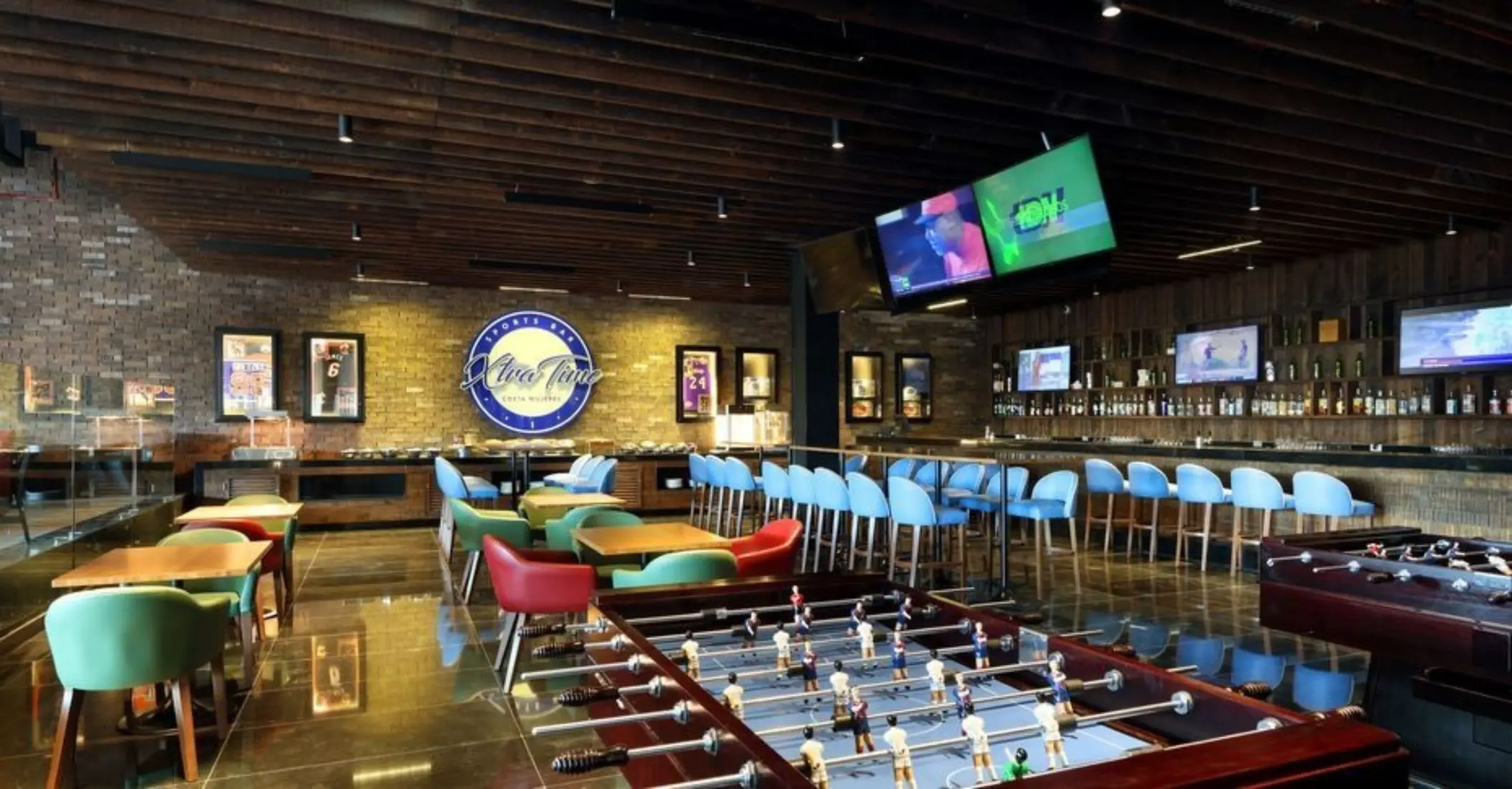 Vibrant sports bar with TVs, foosball tables, and colorful seating at Xtra Time.