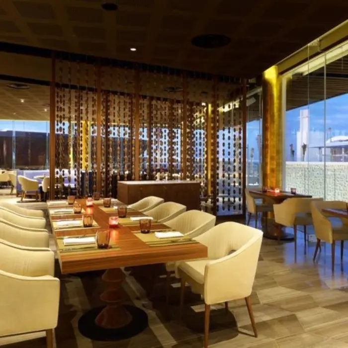 Elegant dining area with cream chairs and warm lighting near large windows at resort restaurant.