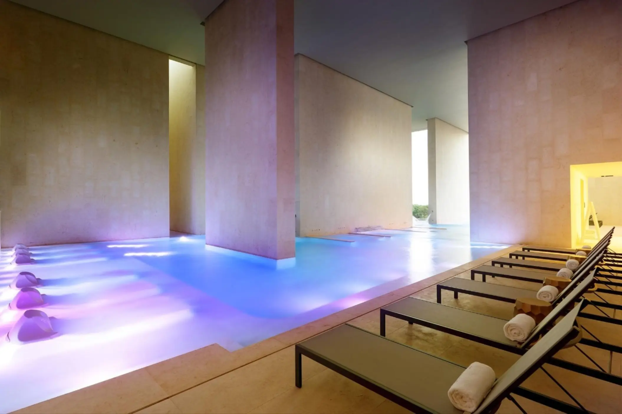 Indoor hydrotherapy pool with mood lighting, loungers, and minimalist design at Zentropia Spa.