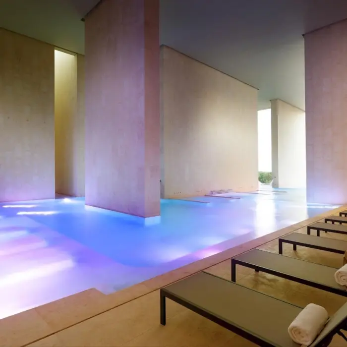 Indoor hydrotherapy pool with mood lighting, loungers, and minimalist design at Zentropia Spa.