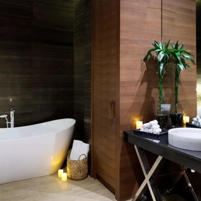 Elegant spa bathroom with a freestanding tub, dark wood walls, soft lighting, and a sleek vanity with candles.