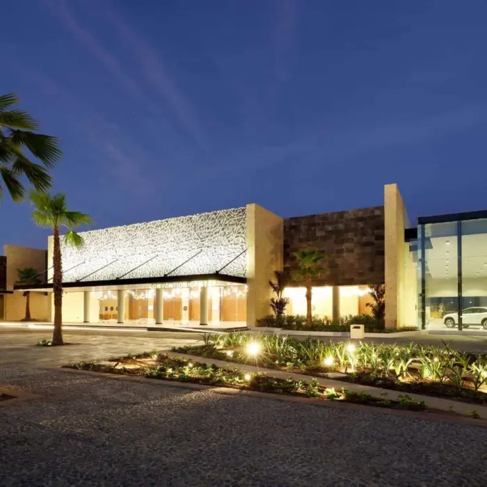 Night view of a modern resort convention center entrance with palm trees and warm lighting.