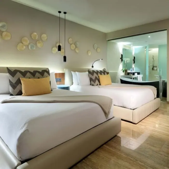 Spacious double-bed suite with chevron pillows, modern decor, and see-through bathroom wall.