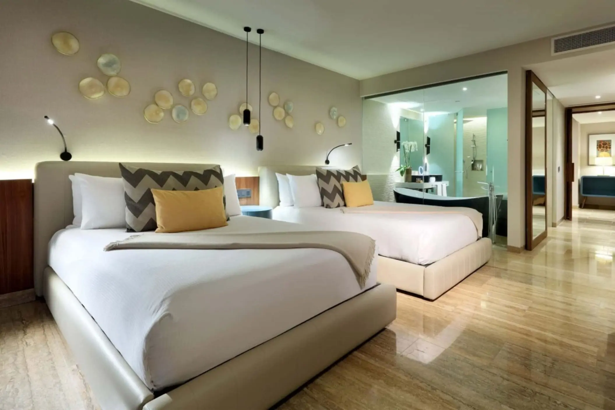Spacious double-bed suite with chevron pillows, modern decor, and see-through bathroom wall.