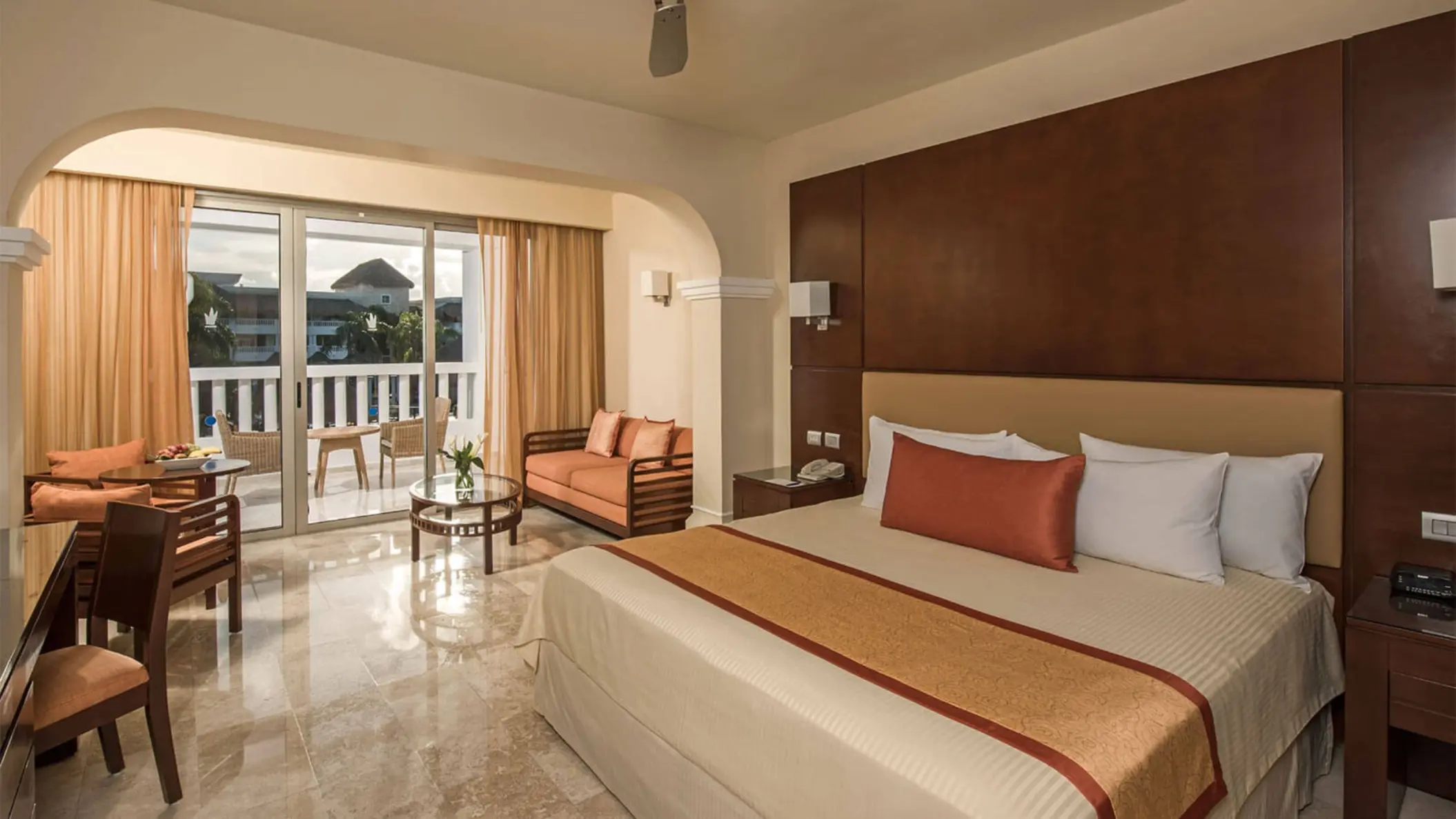 Elegant Junior Suite Deluxe at Grand Riviera Princess with a king-sized bed, sitting area, and balcony.