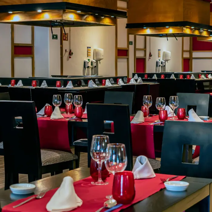 Interior of Grand Riviera Princess's Miso restaurant, set with dark tables, red accents, and Asian-inspired decor.