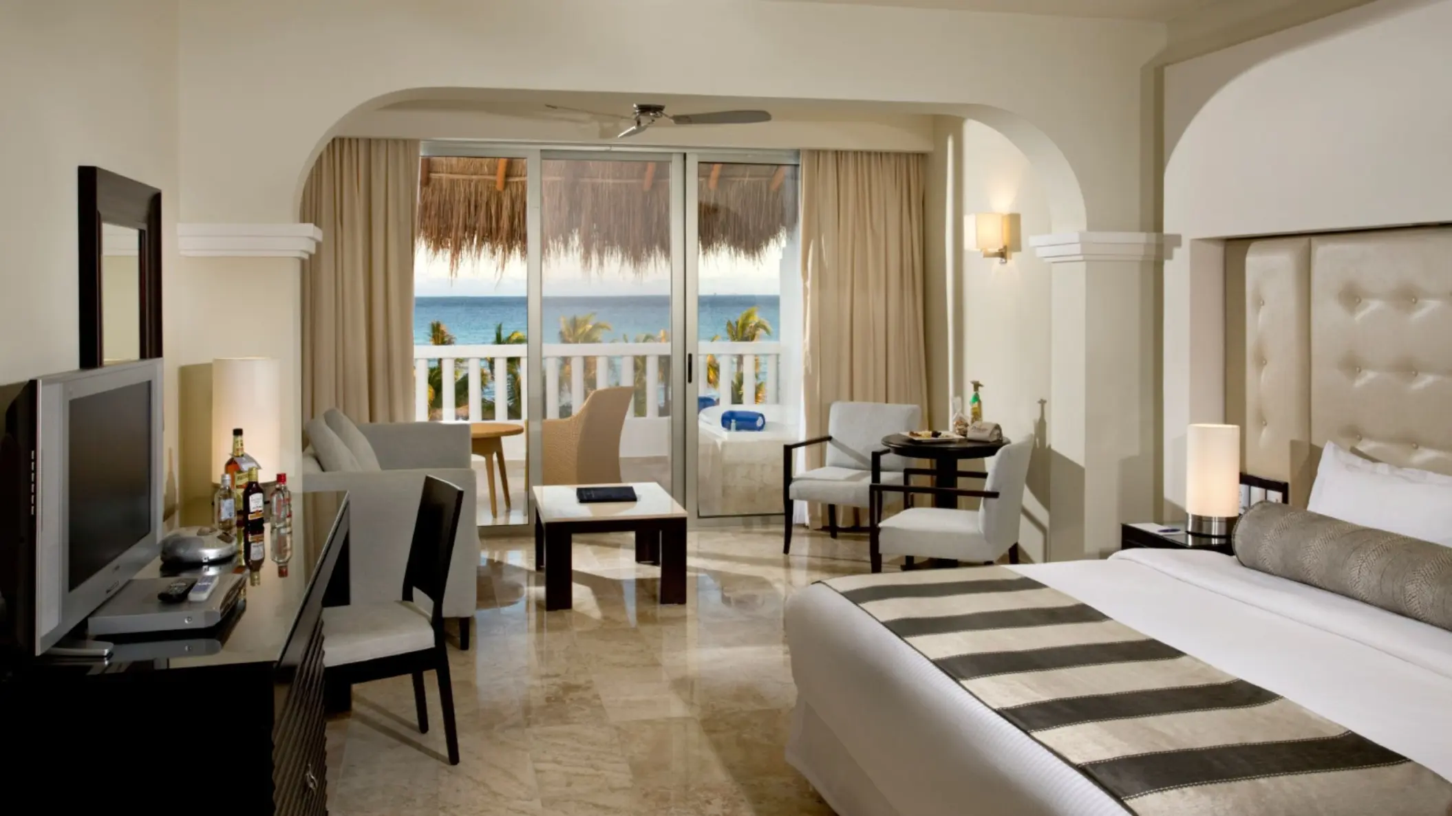 Elegant Platinum Suite at Grand Riviera Princess with ocean views from the balcony, a large bed, and a comfortable sitting area.