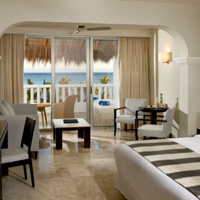 Elegant Platinum Suite at Grand Riviera Princess with ocean views from the balcony, a large bed, and a comfortable sitting area.