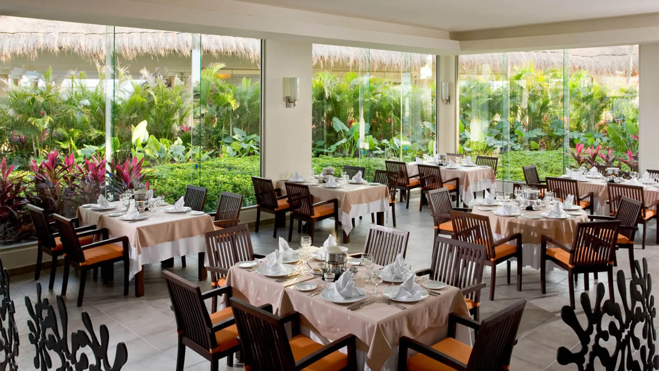 Bright and inviting interior of La Fondue restaurant at Grand Riviera Princess, with tables set and large windows overlooking greenery.