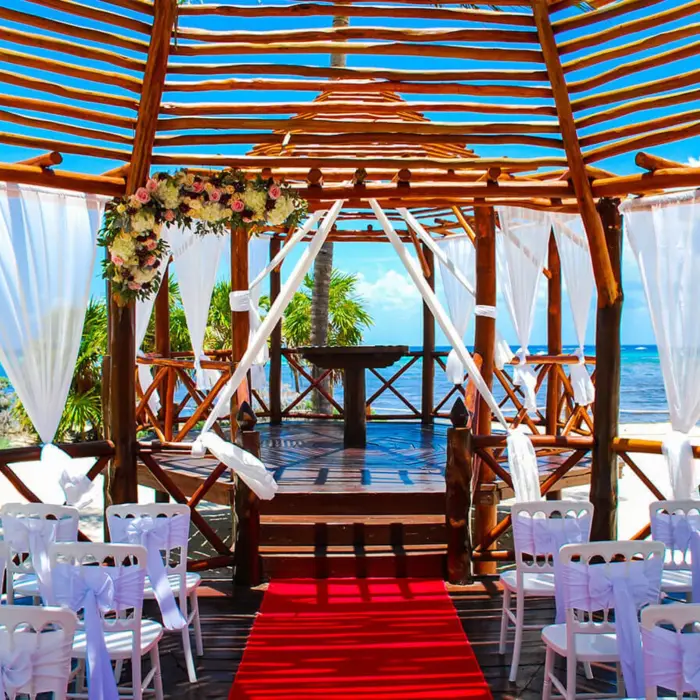 Beautiful beachside wedding gazebo at Grand Riviera Princess, decorated with flowers and white chairs, overlooking the ocean.