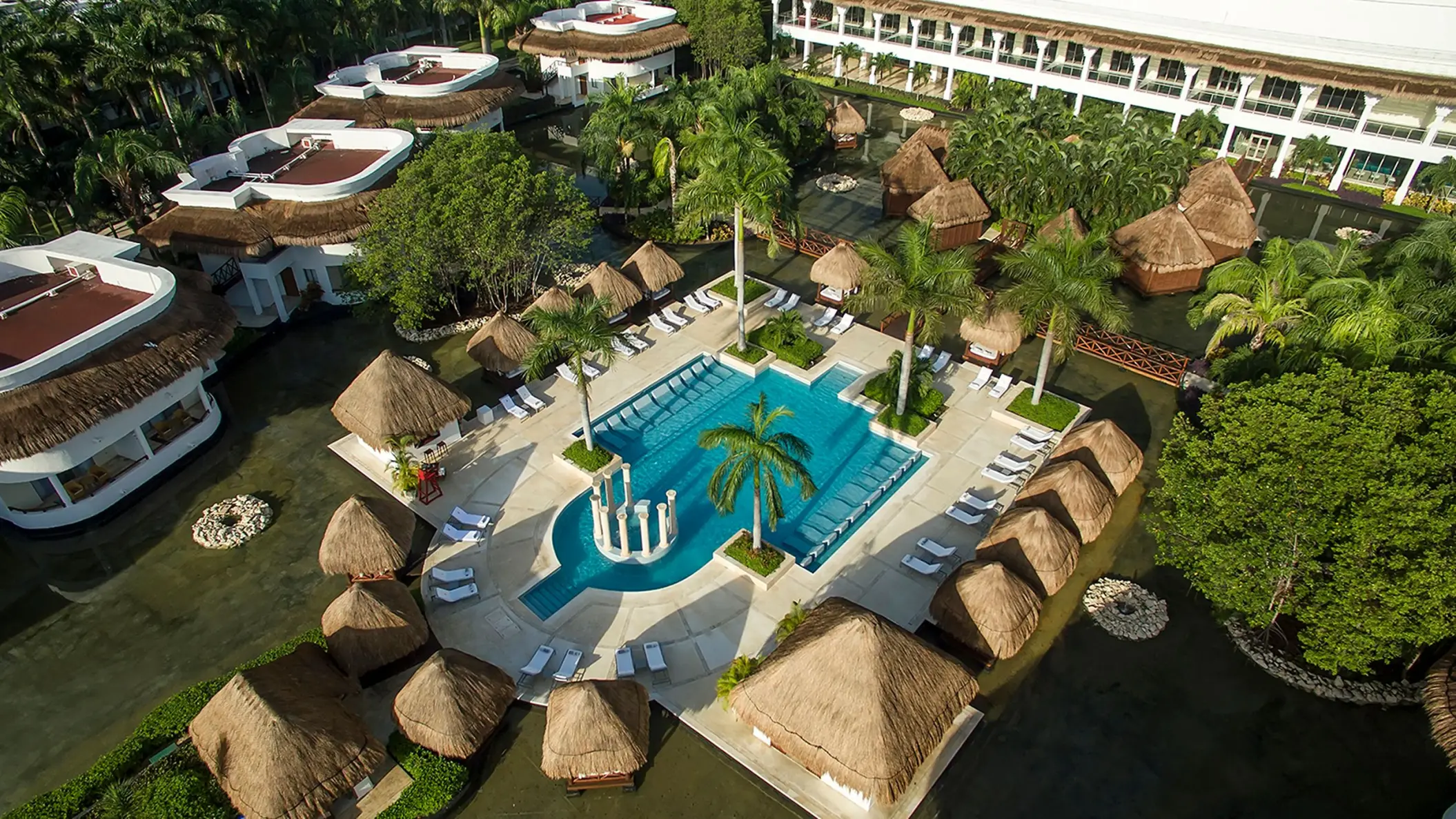 Overhead shot of Grand Sunset Princess resort's lush grounds, a large pool area with loungers, and tropical landscaping.