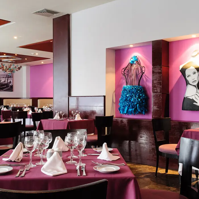 Italian restaurant at Grand Sunset Princess with elegantly set tables, purple accents, and unique artwork on the walls.