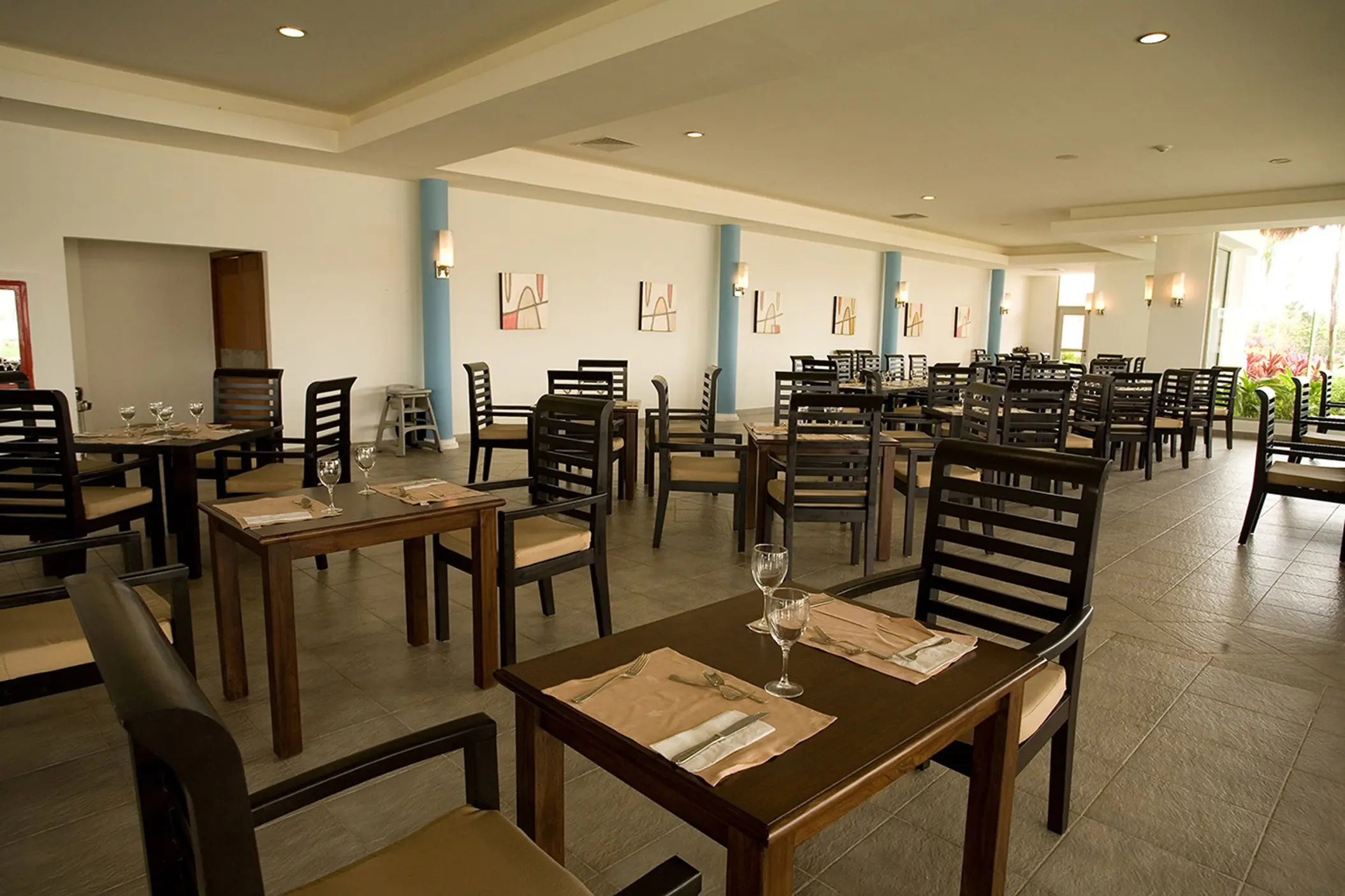 Spacious dining area at Grand Sunset Princess with rows of wooden tables and chairs, and light-colored walls.