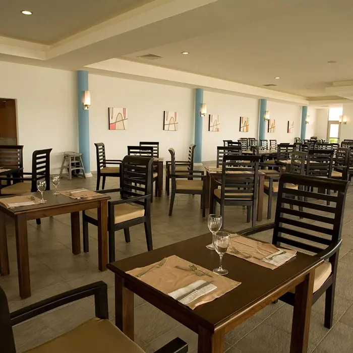 Spacious dining area at Grand Sunset Princess with rows of wooden tables and chairs, and light-colored walls.
