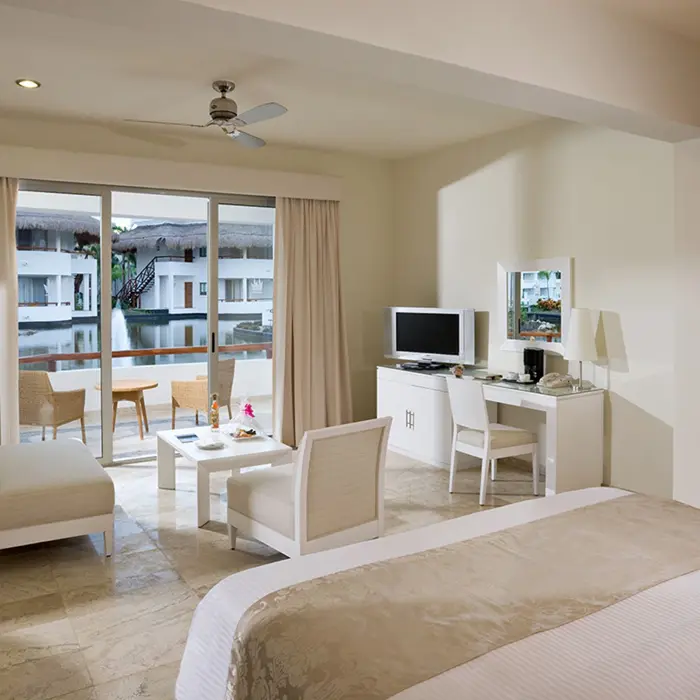 Suite at Grand Sunset Princess with a king bed, living area, and balcony overlooking a serene water canal.