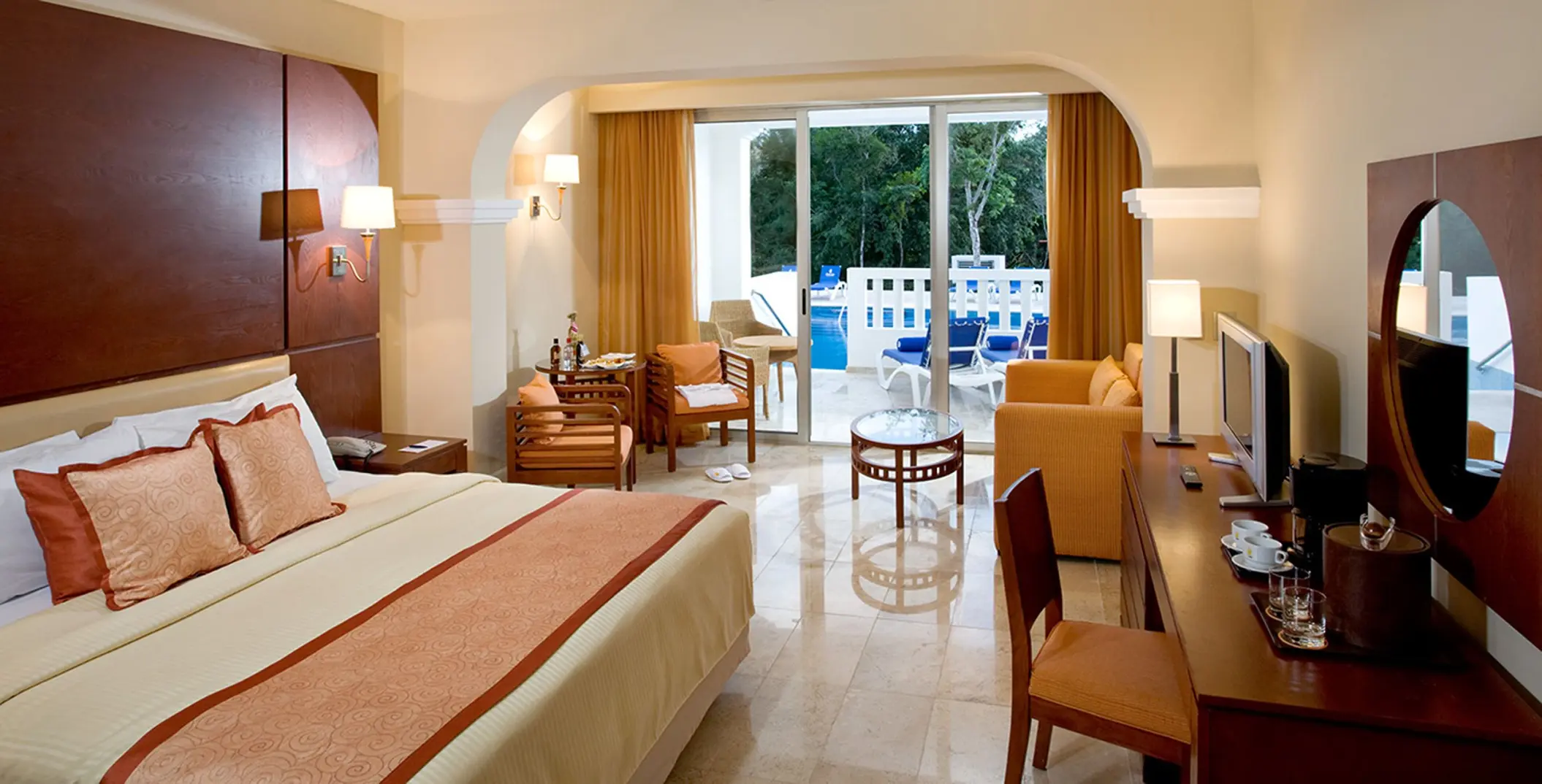 Swim-out suite at Grand Sunset Princess featuring a king bed, living space, and direct access to a pool from the patio.