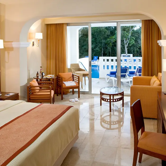 Swim-out suite at Grand Sunset Princess featuring a king bed, living space, and direct access to a pool from the patio.