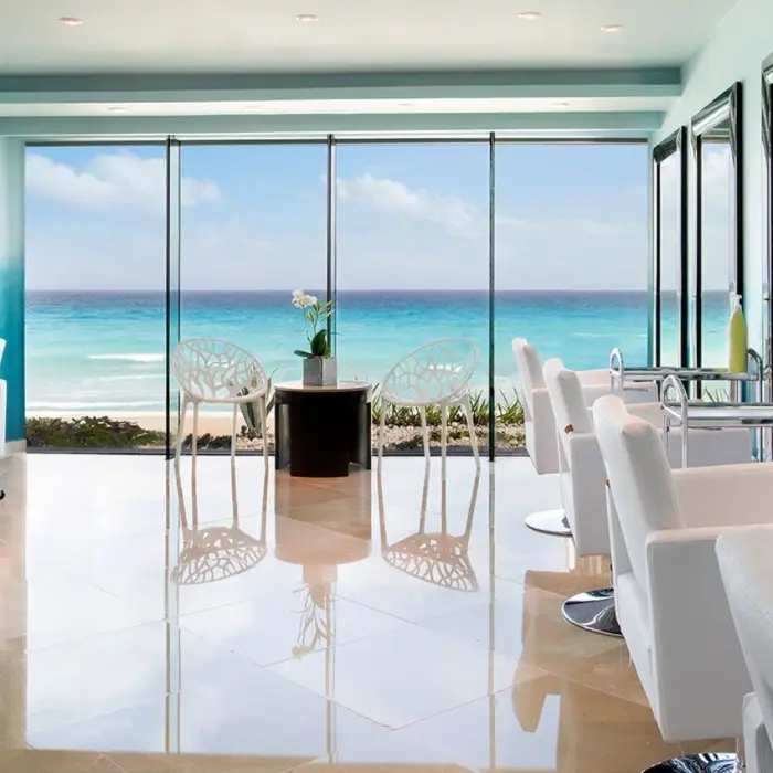 A bright, modern hair salon with multiple stations and a floor-to-ceiling window view of the beach.