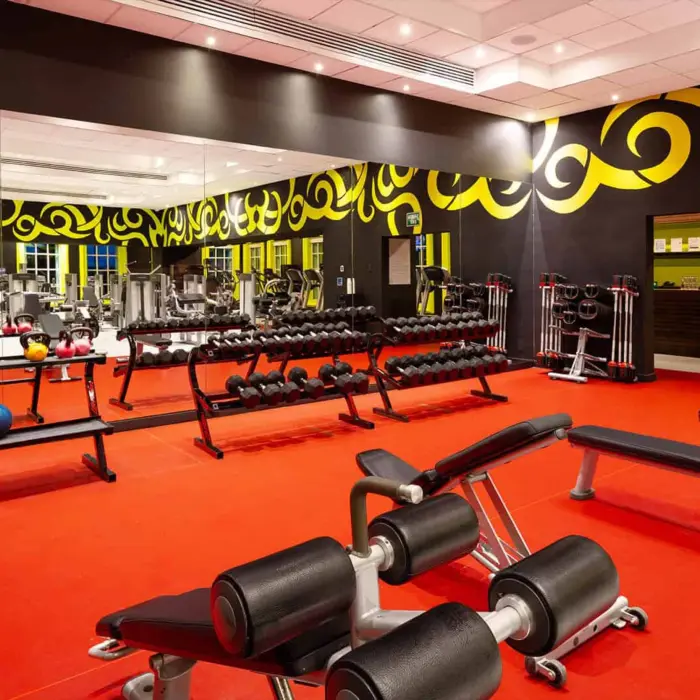 A vibrant and well-equipped gym with red flooring, various weights, and cardio machines.