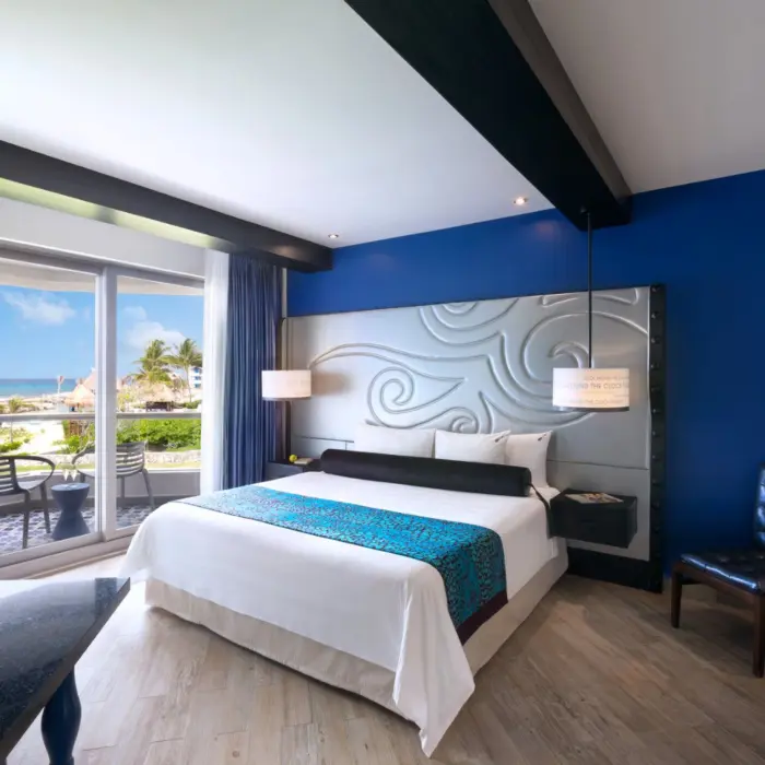 A stylish hotel room with a king-sized bed, a private balcony, and a whirlpool tub in the corner.