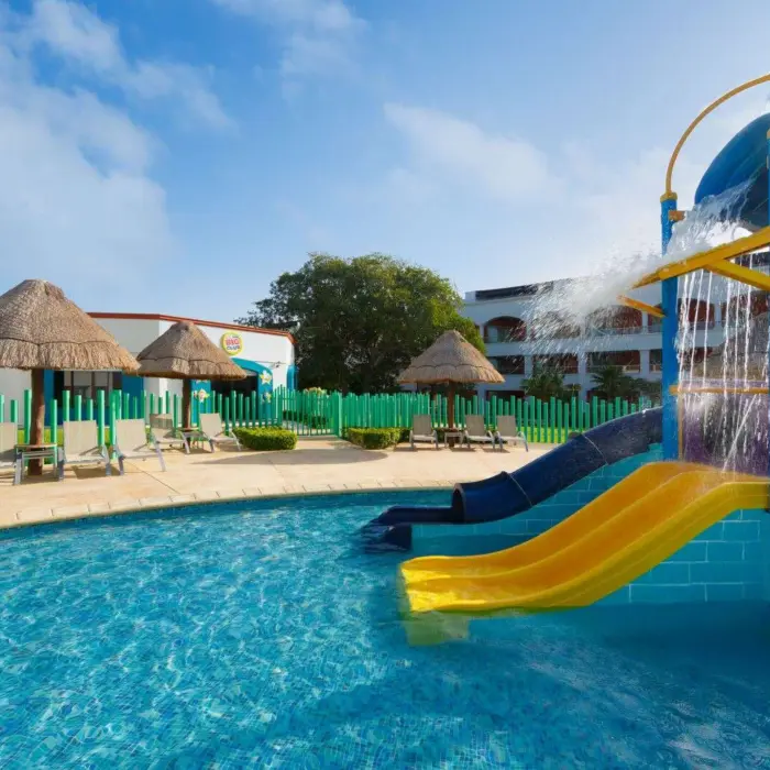 A shallow children's pool with colorful water slides and bright green fences.