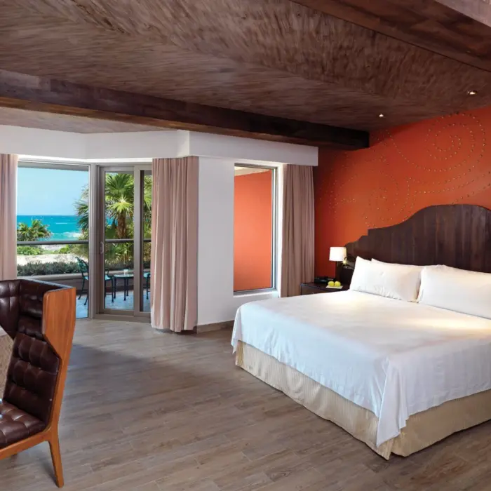 A spacious suite with a king bed, a balcony with an ocean view, and a jacuzzi tub.