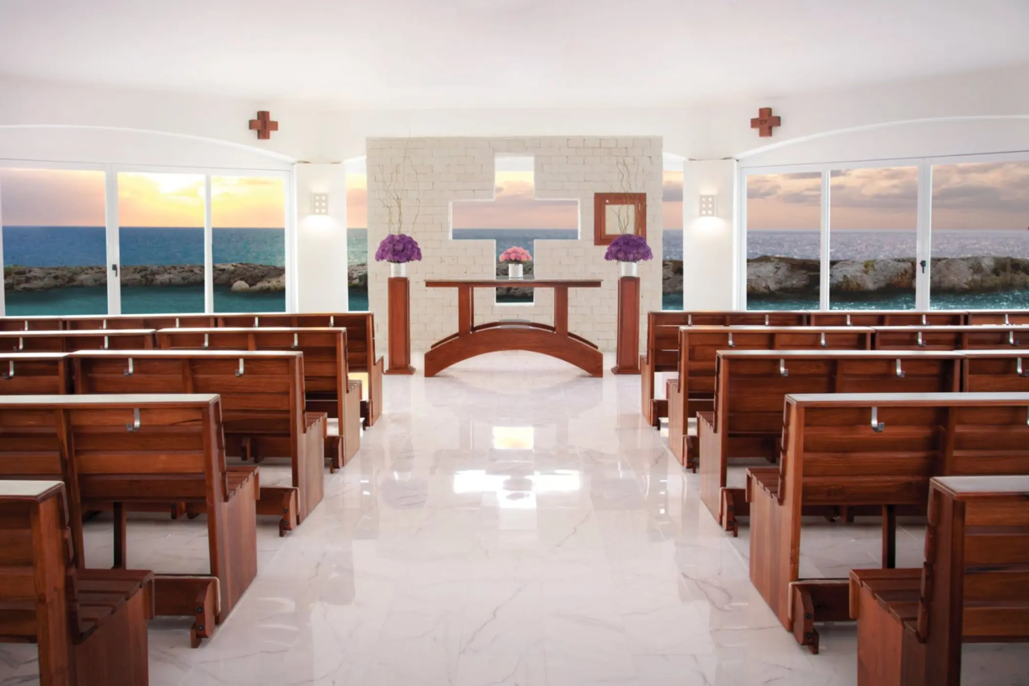 A beautiful indoor wedding chapel with rows of wooden benches and large windows overlooking the ocean.