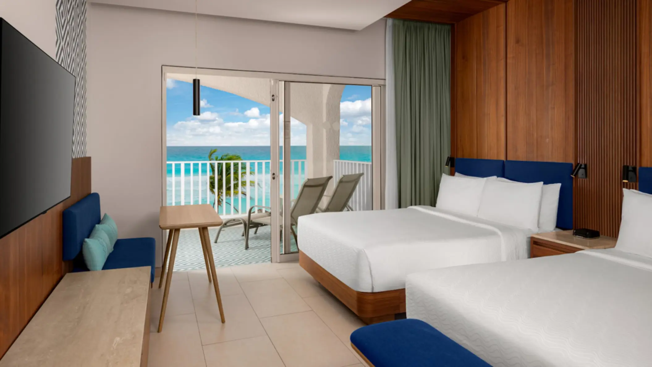 A hotel suite with two double beds, a television, and a balcony with an incredible ocean view.