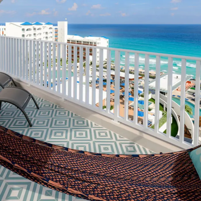 A beautiful balcony with a patterned floor, hammock, lounge chairs, and an expansive view of the ocean.