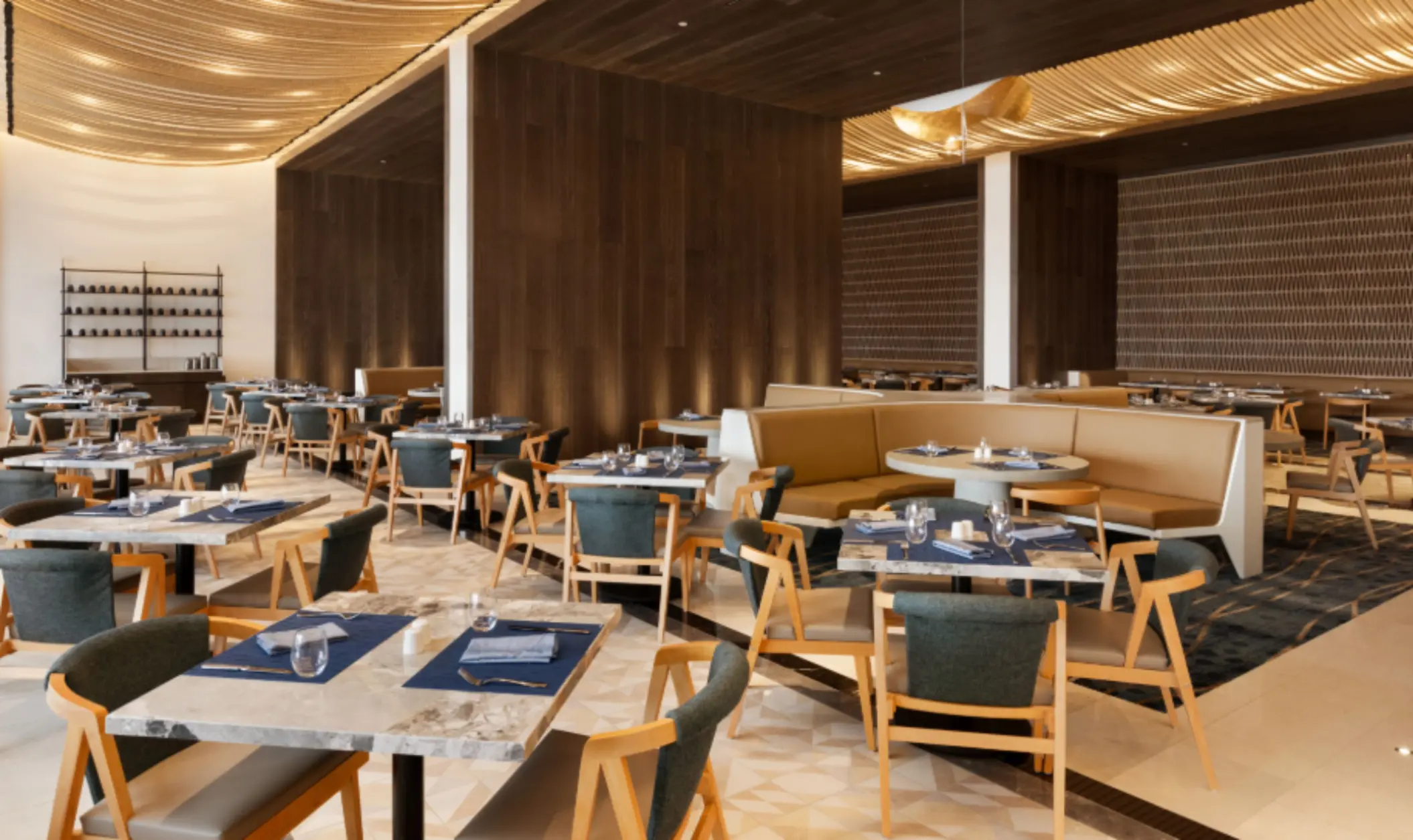 Contemporary restaurant with soft lighting, wood accents, round booths, and marble tables set for a fine dining experience.