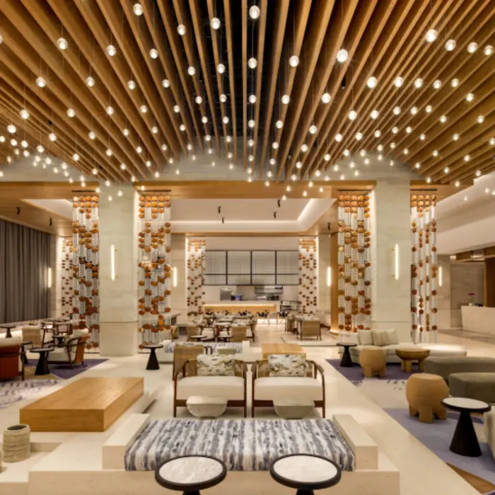 Spacious lobby with wood ceiling slats, pendant lighting, and stylish lounge seating at a luxury beachfront resort.