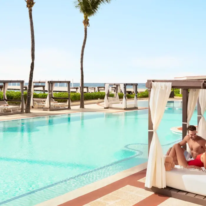 couple lounging by the pool at Hilton Playa del Carmen