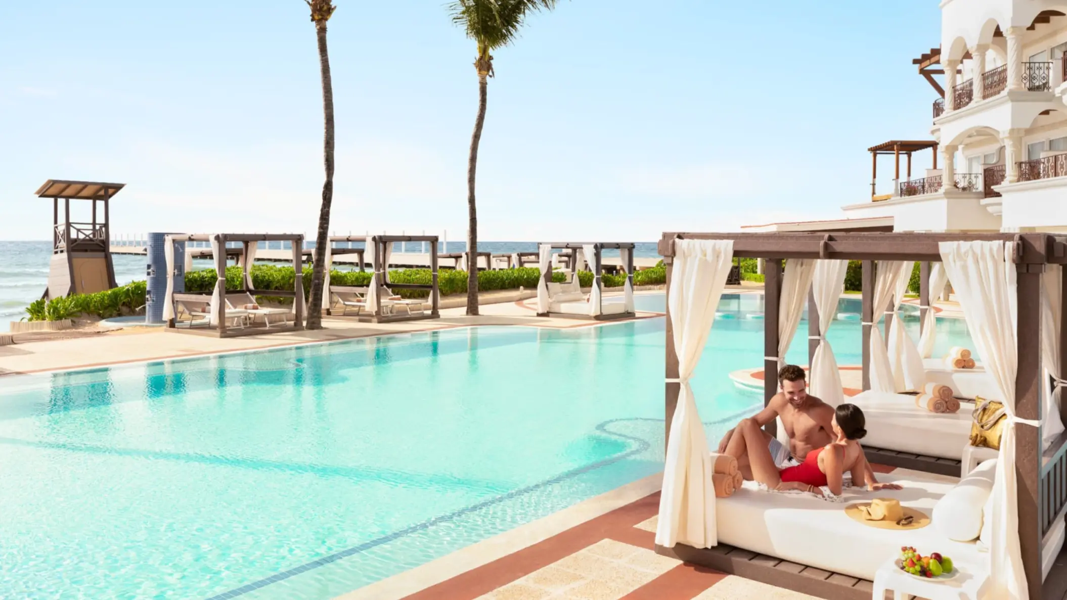 couple lounging by the pool at Hilton Playa del Carmen