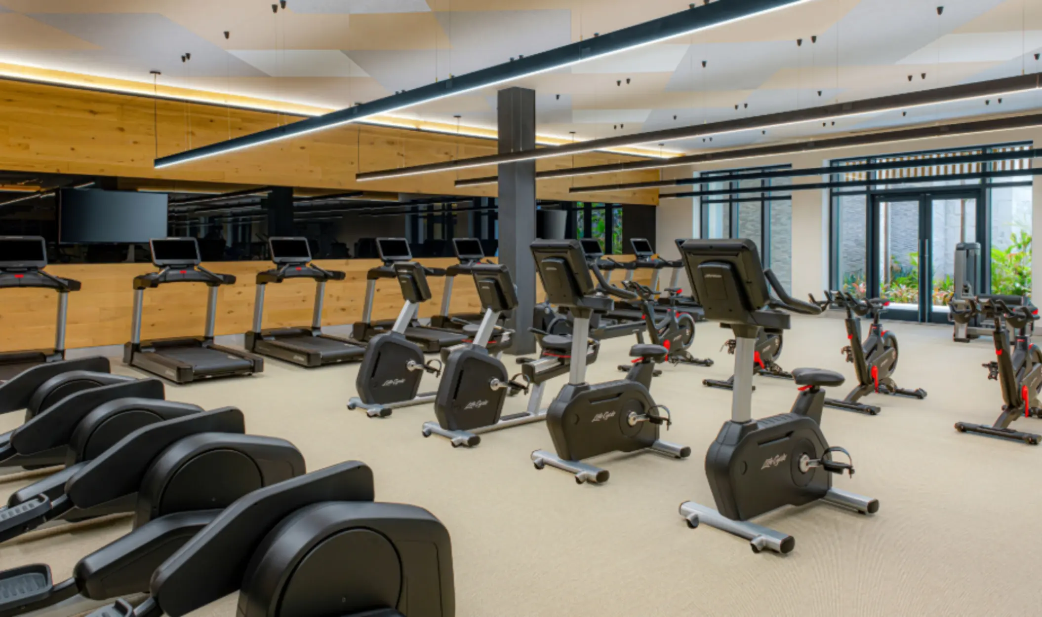 State-of-the-art fitness center with treadmills, spin bikes, and large mirrors reflecting a clean, modern design.