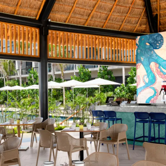 Open-air restaurant with poolside views, tropical decor, and vibrant octopus mural at the colorful bar.