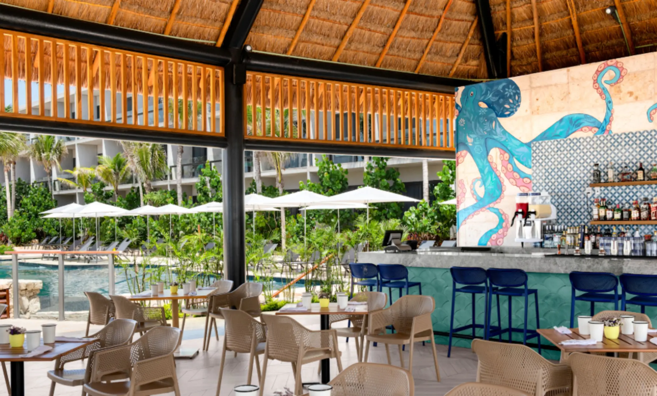 Open-air restaurant with poolside views, tropical decor, and vibrant octopus mural at the colorful bar.