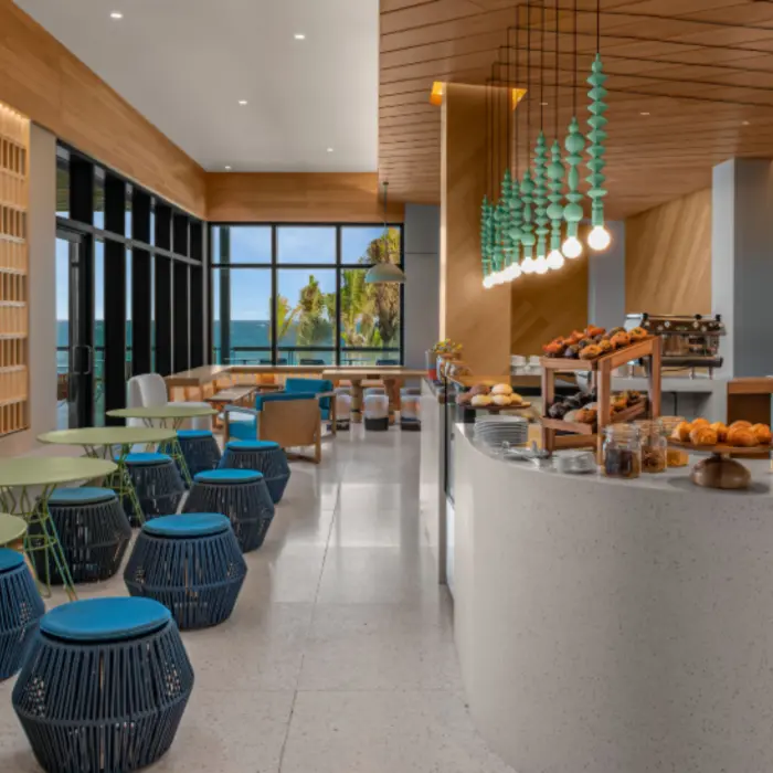 Bright and cozy coffee shop with ocean views, colorful seating, and a variety of pastries and baked goods.