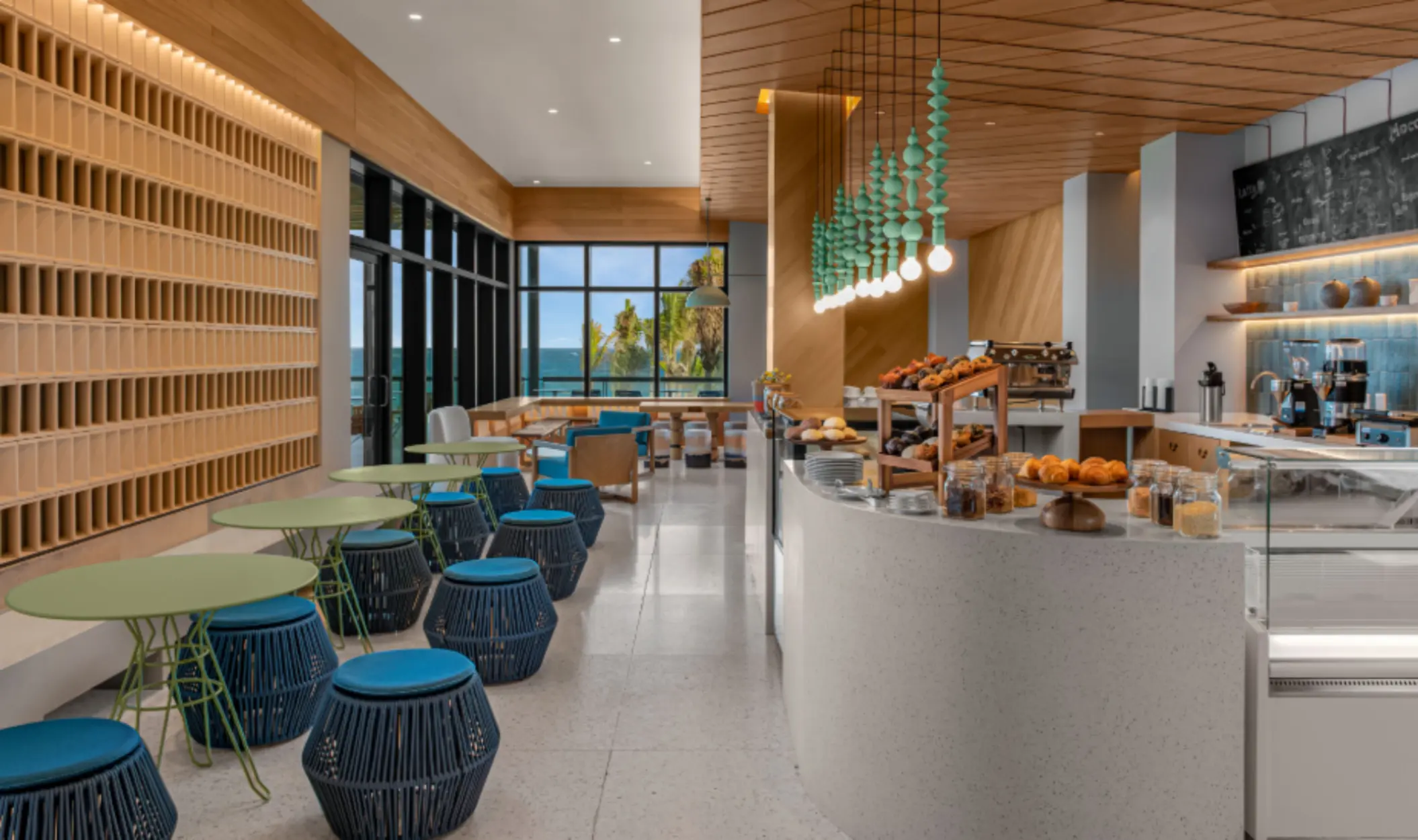 Bright and cozy coffee shop with ocean views, colorful seating, and a variety of pastries and baked goods.