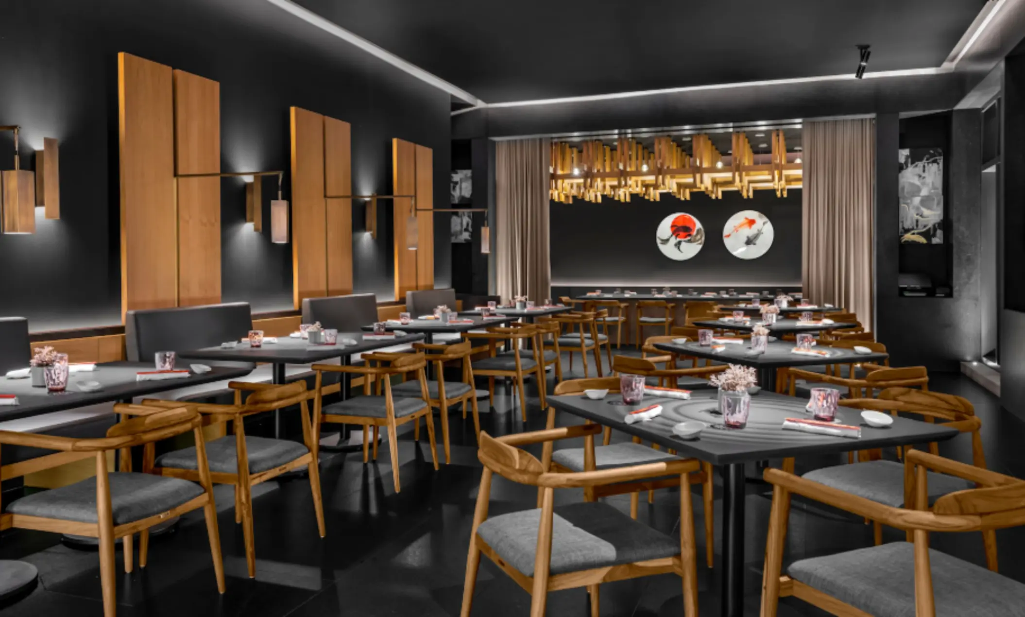 Contemporary black-and-wood Japanese restaurant with koi fish wall art and warm, ambient lighting.