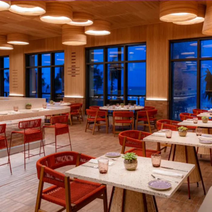 Modern dining room with natural wood accents, ocean views, and warm lighting that creates a cozy ambiance.