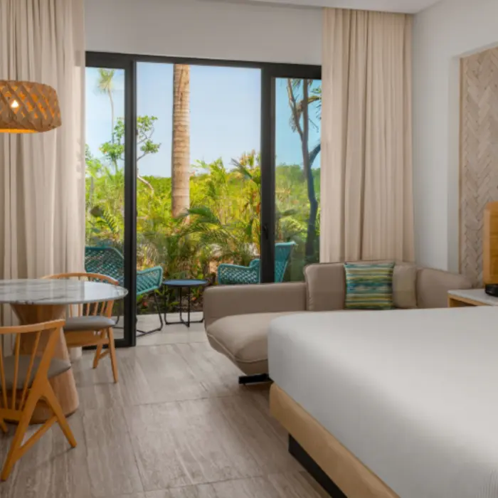 Tropical garden view room with king bed, soft lighting, and a small patio furnished for two.