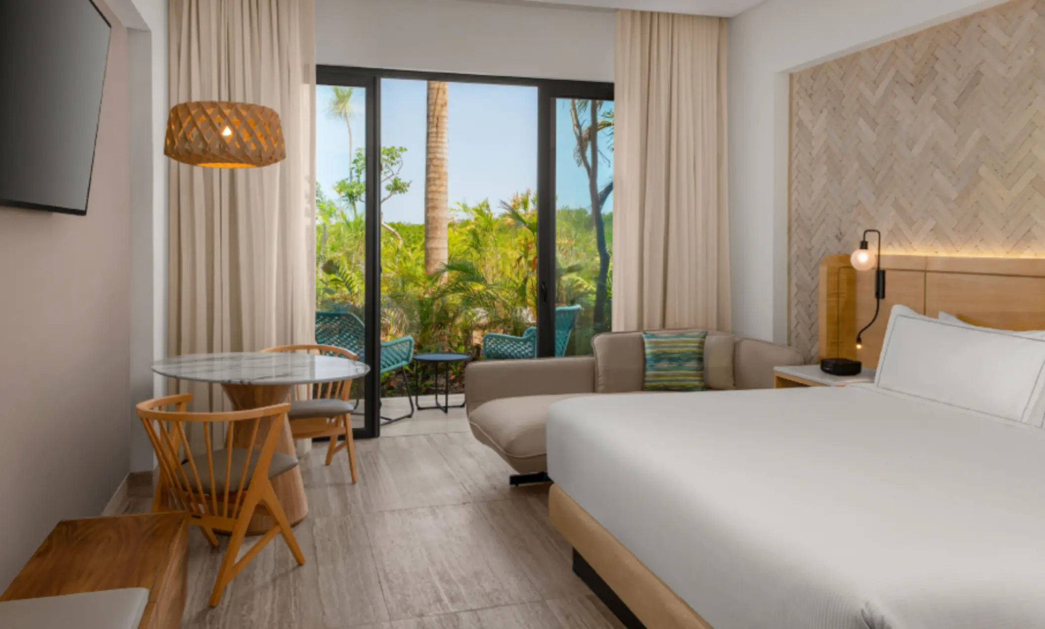 Tropical garden view room with king bed, soft lighting, and a small patio furnished for two.