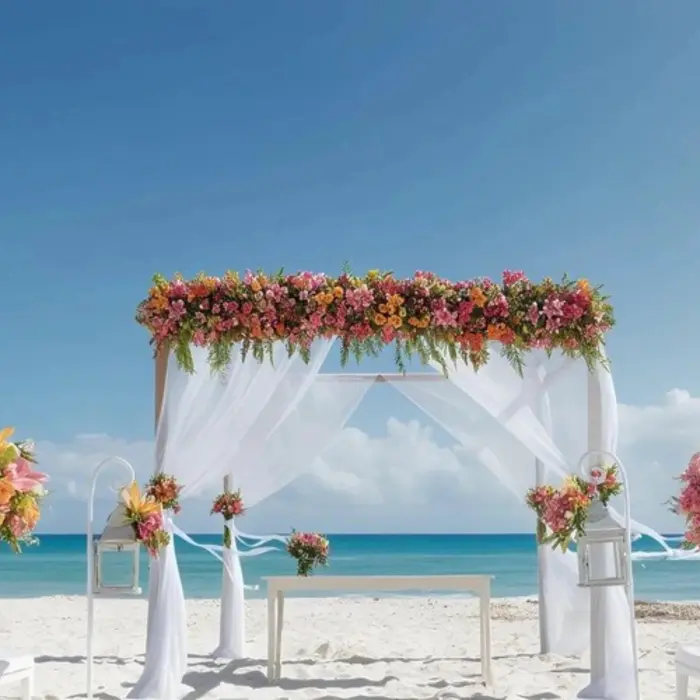 A beautifully decorated beach wedding venue with a floral arch, white chairs, and an altar, overlooking the turquoise ocean.