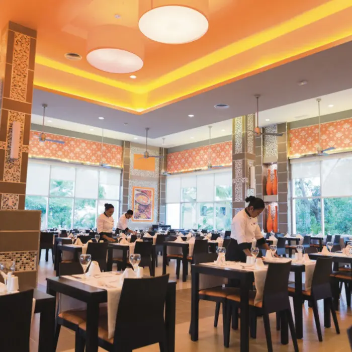 bright and elegant restaurant with neatly set tables, staff preparing for service, and large windows offering outdoor views.
