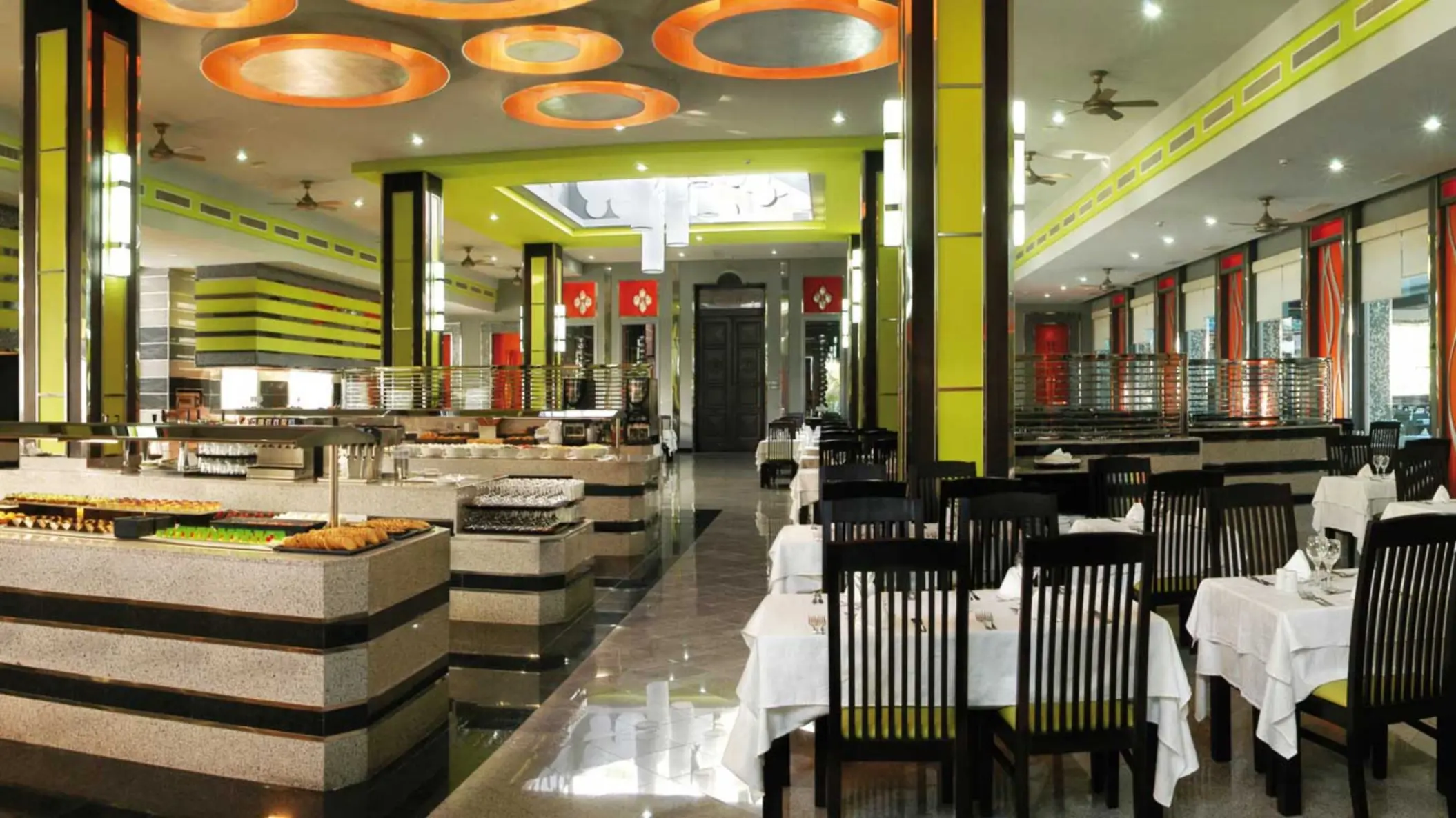 A spacious and modern buffet restaurant with a variety of food stations, ample seating, and bright yellow and white decor.
