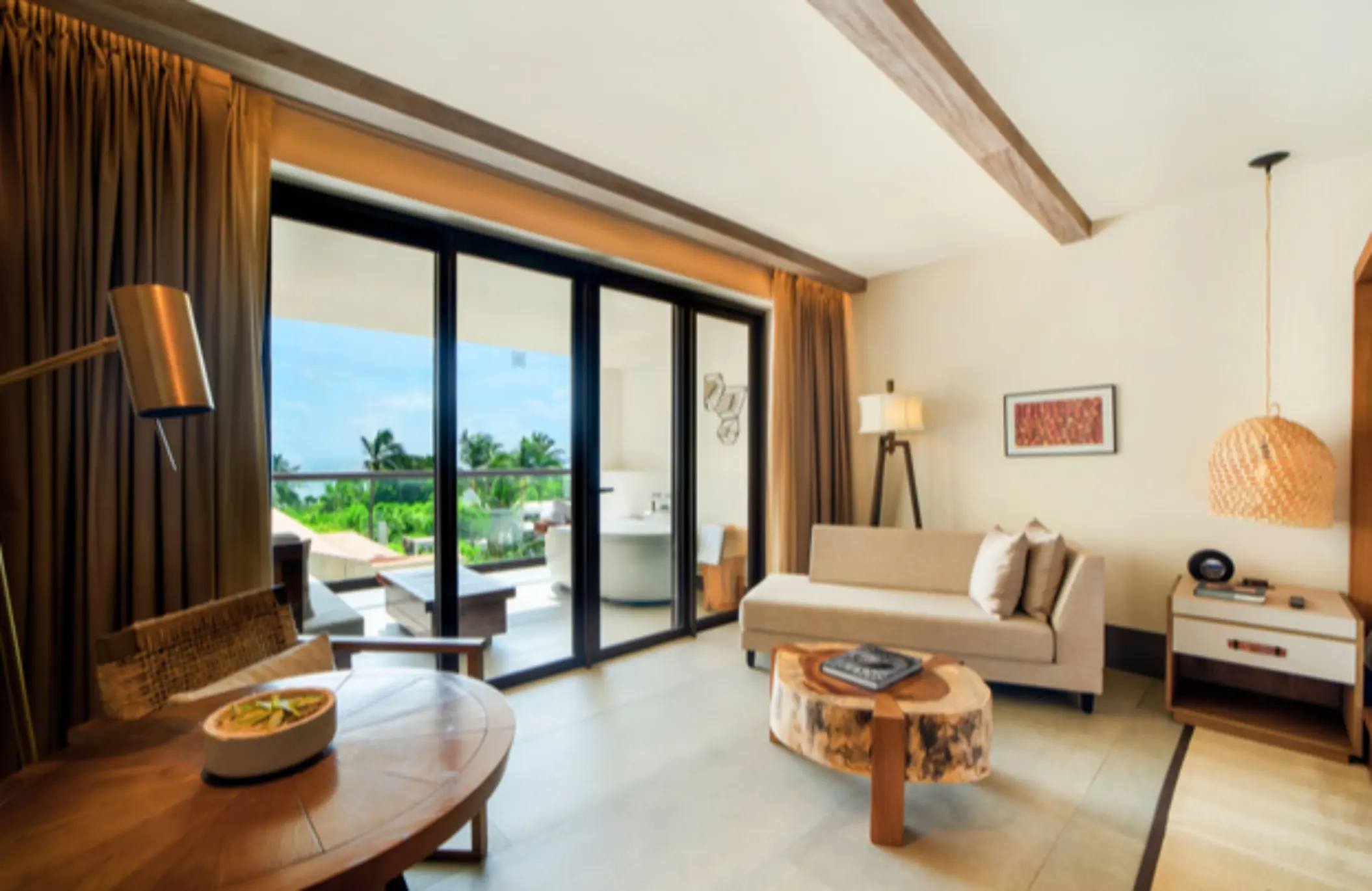 Modern suite living room with natural light, garden views, wood table, and direct access to a private terrace.