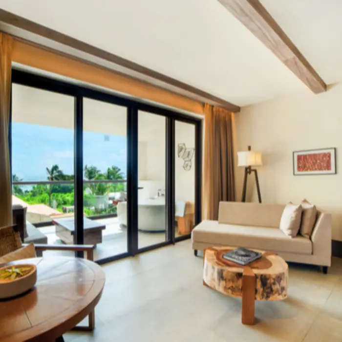Modern suite living room with natural light, garden views, wood table, and direct access to a private terrace.