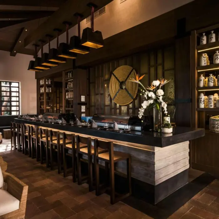 Japanese restaurant with sushi bar, wood accents, dim lighting, and decorative sake jars lining the walls.
