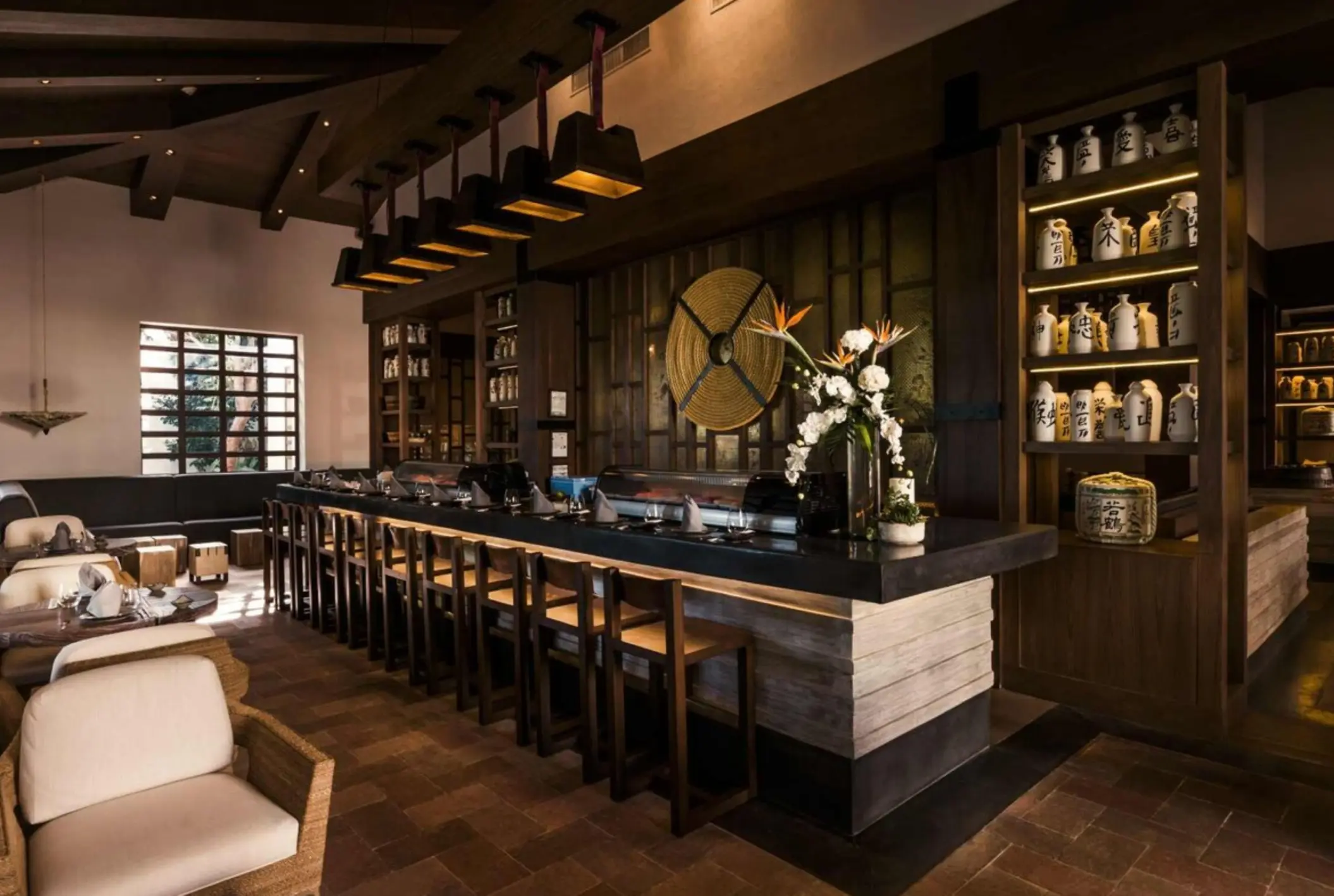 Japanese restaurant with sushi bar, wood accents, dim lighting, and decorative sake jars lining the walls.