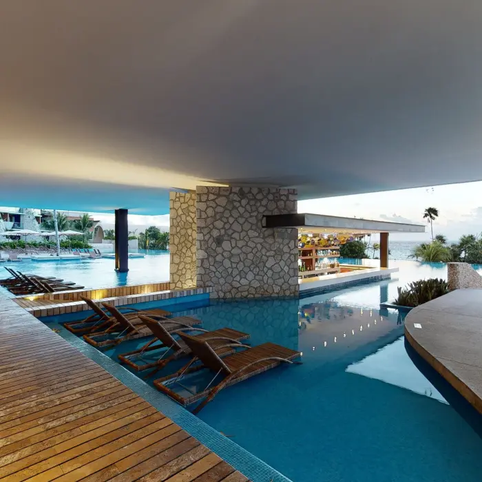 Covered swim-up bar and shaded lounge area with ocean views at Hotel Xcaret Arte.